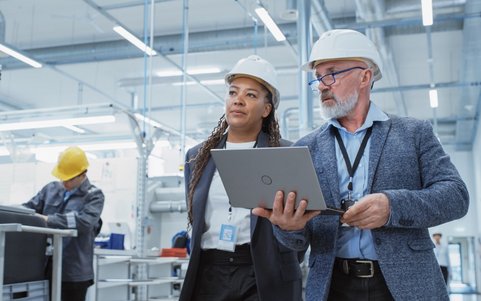 Two occupational safety professionals holding a laptop.
