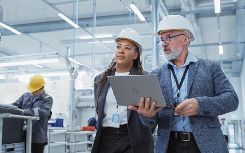 Two occupational safety professionals holding a laptop.
