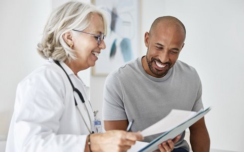 Doctor in a white coat reviewing medical documents with a patient during a consultation.