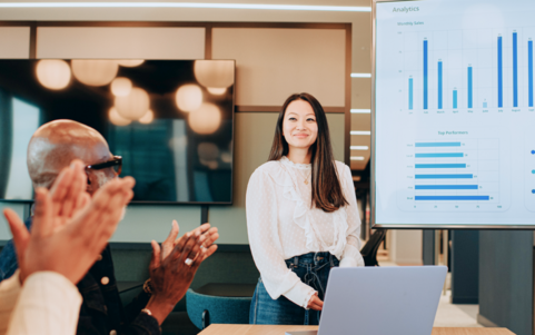 A woman presents performance figures on a screen in the office
