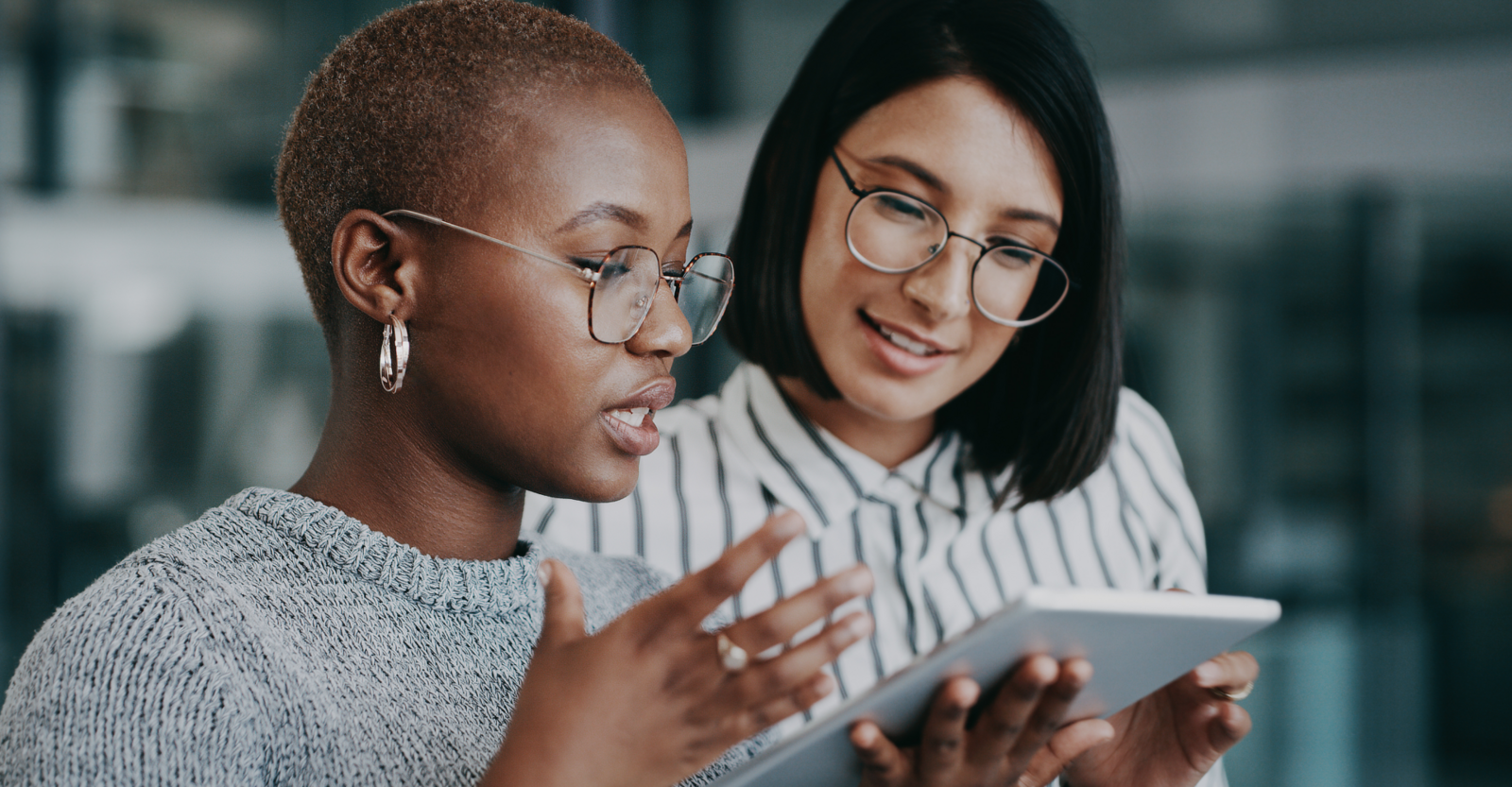 Two employees analyzing information together on a tablet.