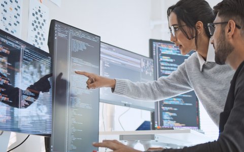 2 Personen die auf Bildschirme mit Code schauen