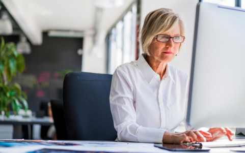 Professional woman working focused at a desktop computer in a bright office
